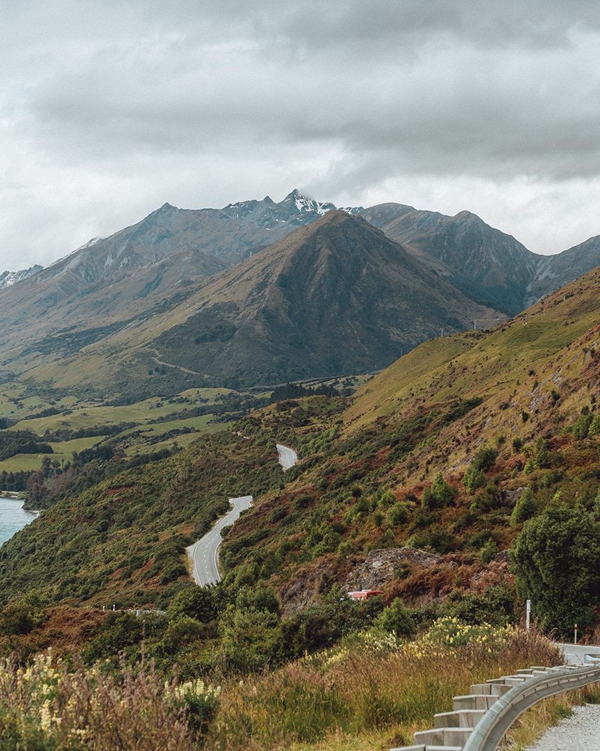 A highway cutting through a mountainous landscape with green slopes.