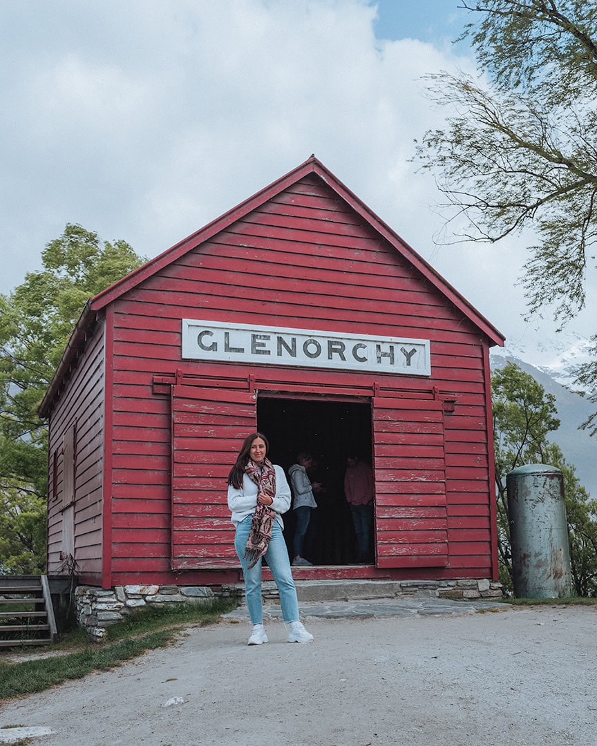 A red hut labeled "Glenorchy" in white letters stands out against a natural backdrop with mountains in the distance.