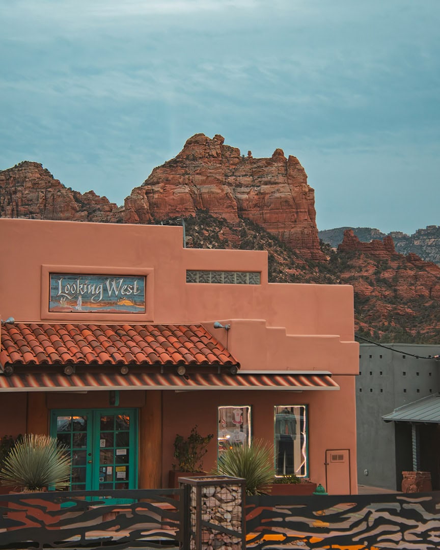 A rustic shop with a southwestern-style adobe exterior, set against red rock cliffs in the background.