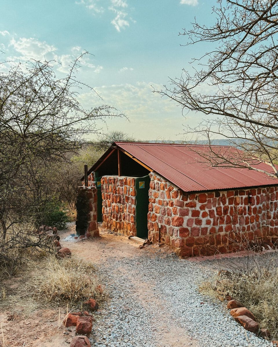 Red stone shower block surrounded by bush at Waterberg Wilderness campsite